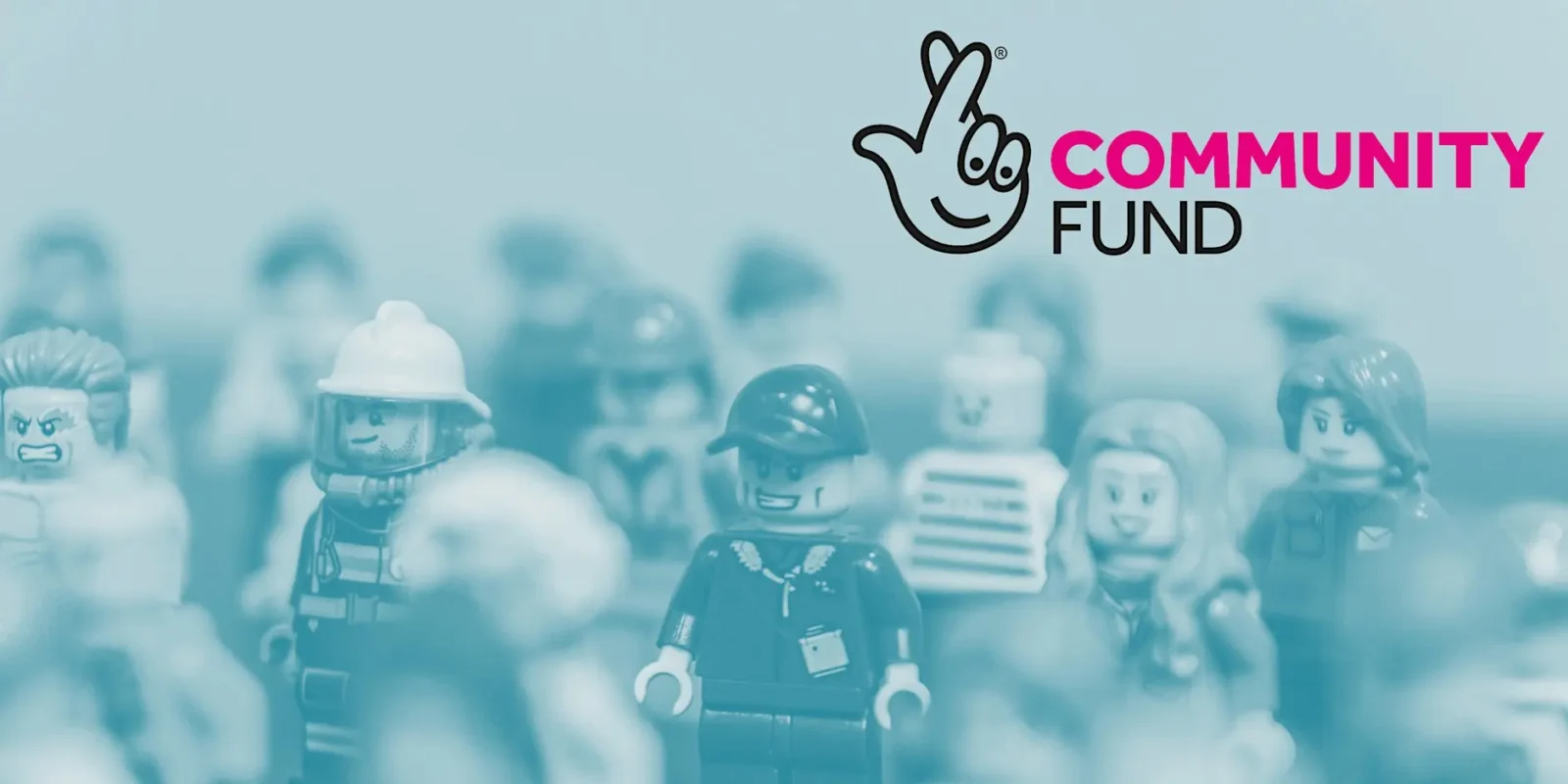 Community Fund logo with crossed fingers symbol above blurred LEGO minifigures in blue tones.